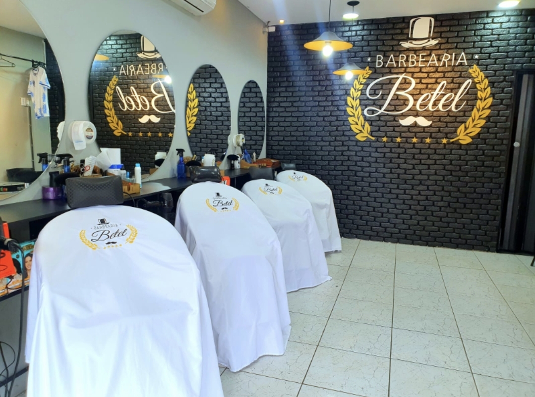 Salão da Barbearia Betel Japuí com parede de tijolos e logo dourado